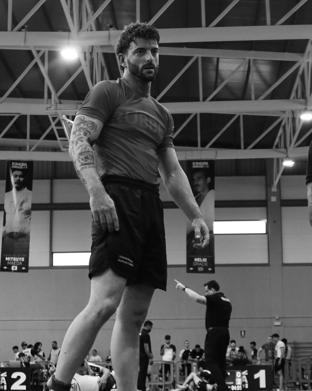 Male athlete in rashguard and shorts at jiu jitsu tournament, gym setting, competition
